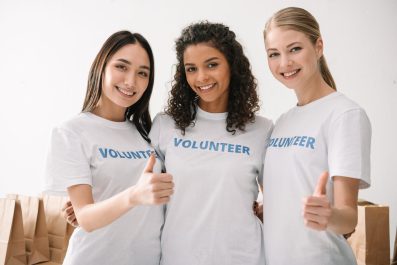 group of happy female volunteers showing thumbs up